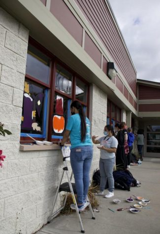 Students paint the windows at the Monroe Free Library as part of an annual Halloween event