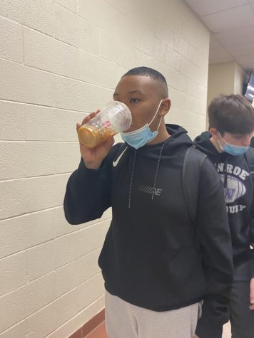 Senior Christopher Nobles drinking coffee on his way to his next class.