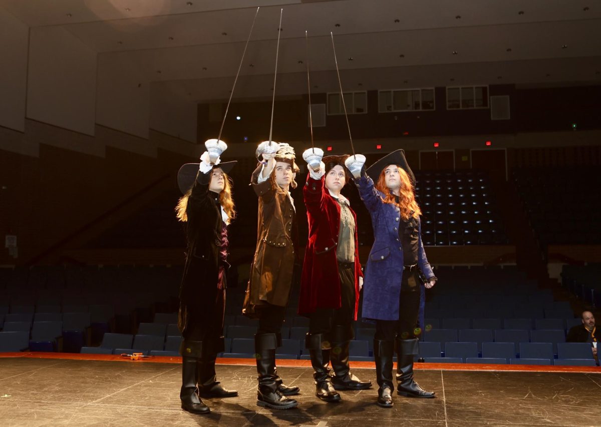 Porthos, D'Artagnan, Athos, and Aramis, the titular musketeers and main characters in the play, pose with rapiers raised together. From left to right: Daniel Solano as Porthos, Tyler Landusky as D'Artagnan, Jacob Ciriello as Athos, and Kenneth Giacomazza as Aramis.