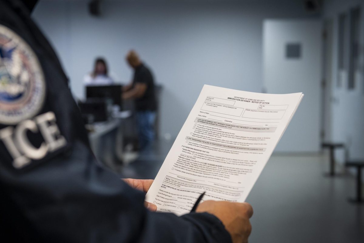 An ICE officer holding an Immigration Detainer form taken at a detention facility.